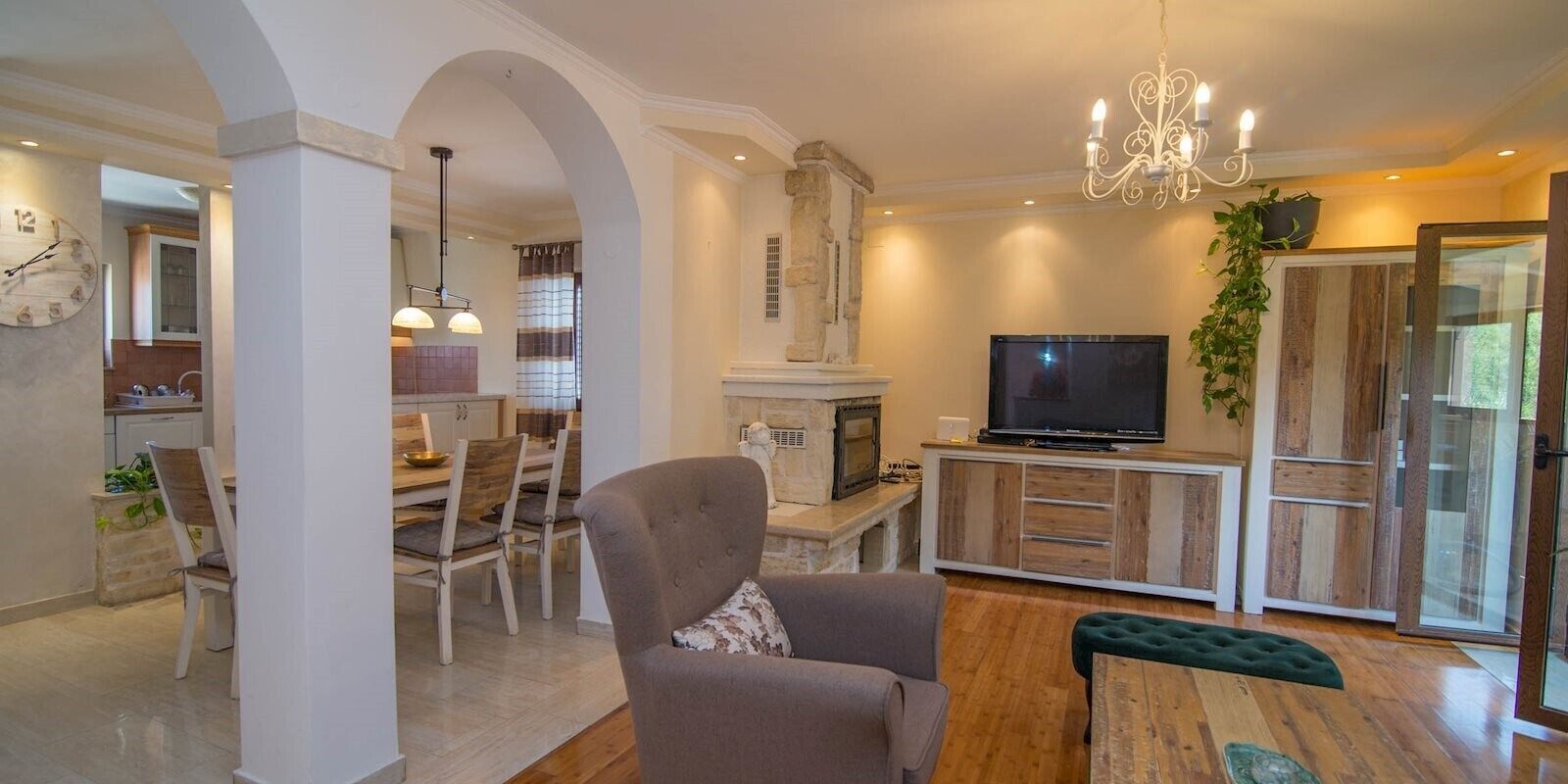 Ein modernes Wohnzimmer mit Kamin, Fernseher und Essbereich mit Holzsesseln und Tisch.