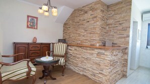 Un comedor con pared de piedra, mobiliario de madera y una araña.