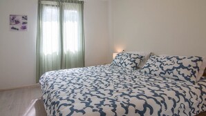 A bedroom with a bed, a nightstand, a lamp, and a window with curtains. - Ivana C6 in Veli Lošinj (Veli Lošinj)