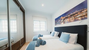 A hotel room with two beds, a large window, a cityscape painting, and a sliding door. - Holiday Home 'Douro Garden Home Rooftop' with Private Terrace, Wi-Fi and Air Conditioning (Vila Nova de Gaia)
