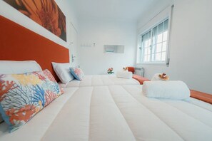 Una camera d'albergo con un letto, cuscini, una finestra e un termosifone.