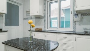 A kitchen with white cabinets, a granite countertop, and a window with a view. - Holiday Home 'Douro Garden Home Rooftop' with Private Terrace, Wi-Fi and Air Conditioning (Vila Nova de Gaia)