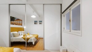 A room with a bed, a bench, a sliding door, and a window.