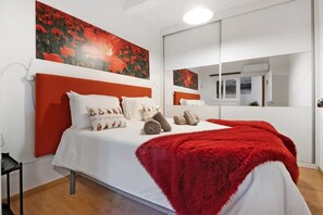 A modern hotel room with a large bed, white bedding, red accents, and artwork on the walls. - Holiday Home 'Douro Garden House and Pool' with Private Pool, Wi-Fi and Air Conditioning (Vila Nova de Gaia)