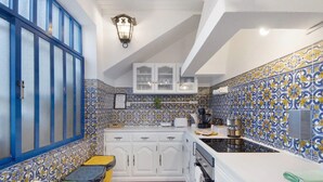 A kitchen with white cabinets, a tiled backsplash, and a hanging light fixture.