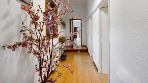 A hallway with a wooden floor, white walls, and a large mirror.