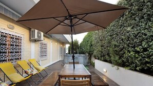 An outdoor patio with a table and chairs, a large umbrella, and a decorative wall with patterned metalwork.