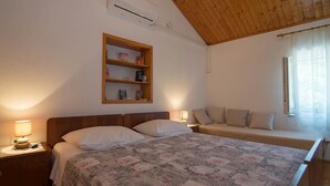 Een slaapkamer met een bed, nachtkastjes, een wandplank en een raam met gordijnen.