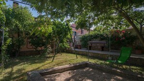 Een tuin met een stenen plantenbak, een groene stoel en een schommel.