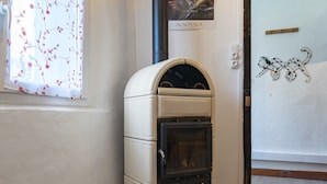 A compact, white, wall-mounted oven with a black door, positioned in a corner of a room with wooden flooring and a white wall. - House in a Hamlet in the Heart of Cathar Country (Quillan)