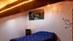 A bedroom with a bed, a wall-mounted heater, a painting, and a wooden ceiling. - House in a Hamlet in the Heart of Cathar Country (Quillan)