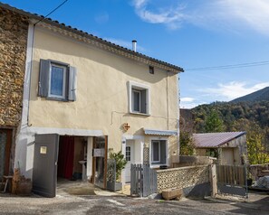 Un bâtiment à deux étages, doté d’une façade en pierre, d’un petit porche et d’un portail.