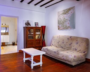 A living room with a wooden cabinet, a sofa, a table, and a map on the wall. - House in a Hamlet in the Heart of Cathar Country (Quillan)