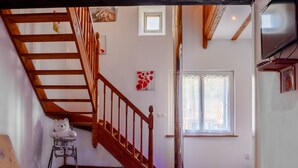 A room with a wooden staircase, a white sofa, a small table, a teddy bear, and a window with a view. - House in a Hamlet in the Heart of Cathar Country (Quillan)