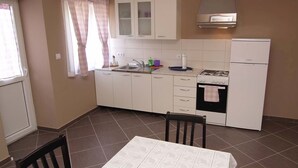 Una cucina compatta con pensili bianchi, piano cottura a gas, forno integrato e lavello.