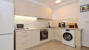 Eine moderne Küche mit weißen Schränken, einer Mikrowelle, einem Backofen, einem Geschirrspüler und einer Kaffeemaschine.