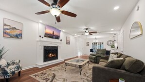 A spacious living room with a fireplace, a sofa, a coffee table, and a ceiling fan. - 5BR Smyrna Home Near the Battery (Smyrna)
