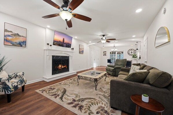 A spacious living room with a fireplace, a sofa, a coffee table, and a ceiling fan. - 5BR Smyrna Home Near the Battery (Smyrna)