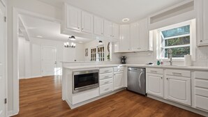 A modern kitchen with white cabinetry, a built-in oven, and a dishwasher. - 5BR Smyrna Home Near the Battery (Smyrna)