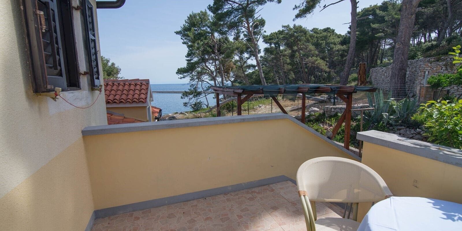 Een balkon met uitzicht op zee, een tafel en een stoel.