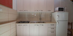 Een koelkast, een kookplaat, kookgerei, borden en bestek