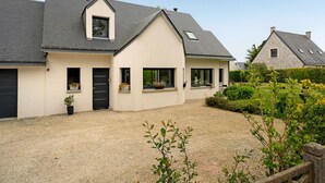 Ein zweistöckiges Haus mit Kiesweg, einer schwarzen Tür und einem kleinen Garten mit Kübelpflanzen.