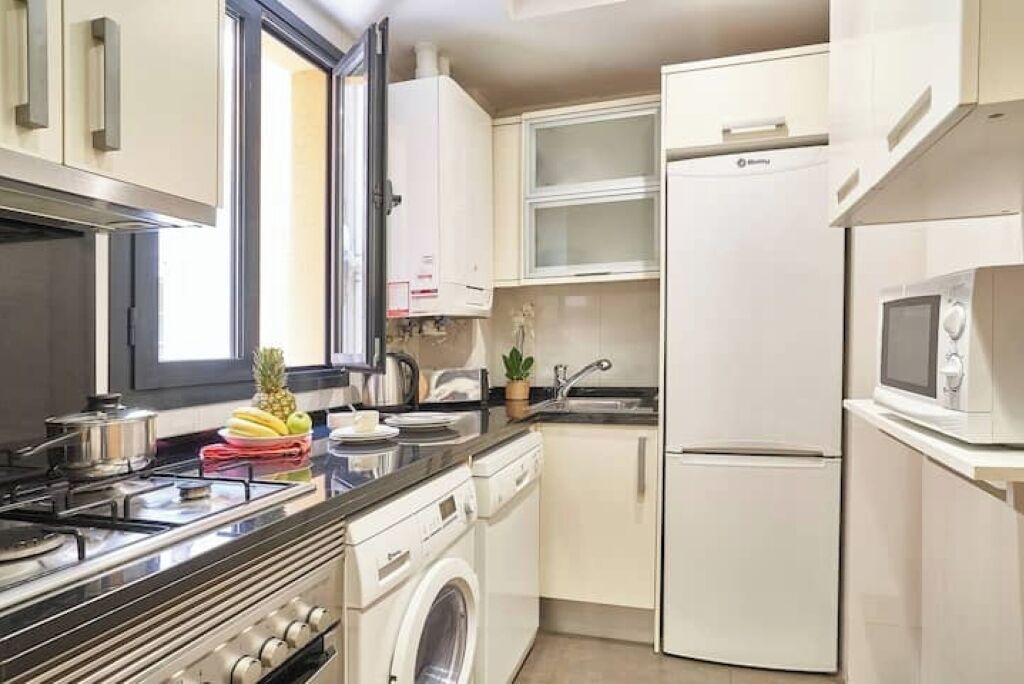 A compact kitchen with a stove, microwave, and a washing machine.