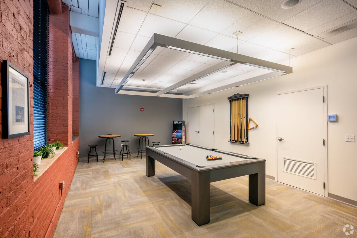 A billiards room with a pool table, stools, and a dartboard.