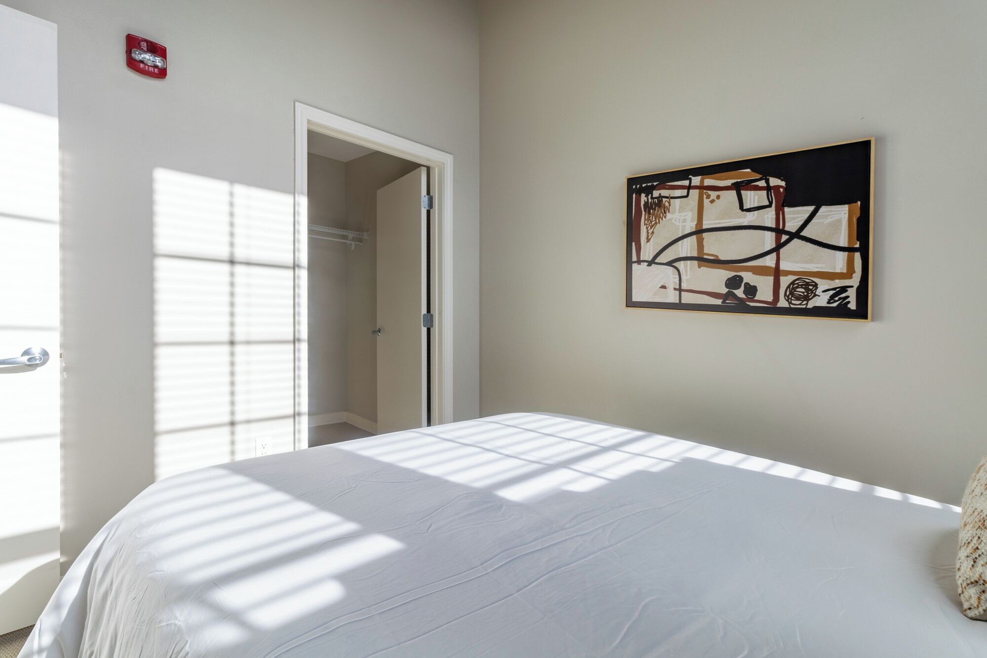 Un dormitorio con cama, una puerta, un armario y un cuadro en la pared.