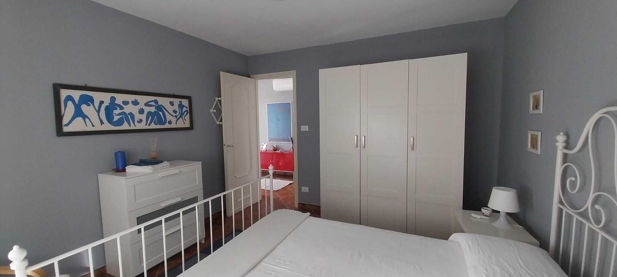 Une chambre à coucher avec un lit, une commode, une armoire et un tableau accroché au mur.