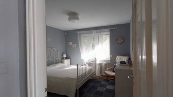 A bedroom with a bed, bedside table, lamp, and a window with curtains.