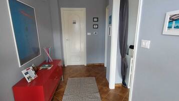 A hallway with a red console table, a grey rug, and a door leading to another room.