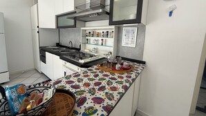 Une cuisine moderne avec des meubles blancs, une cuisinière en acier inoxydable et un plan de travail aux couleurs vives.