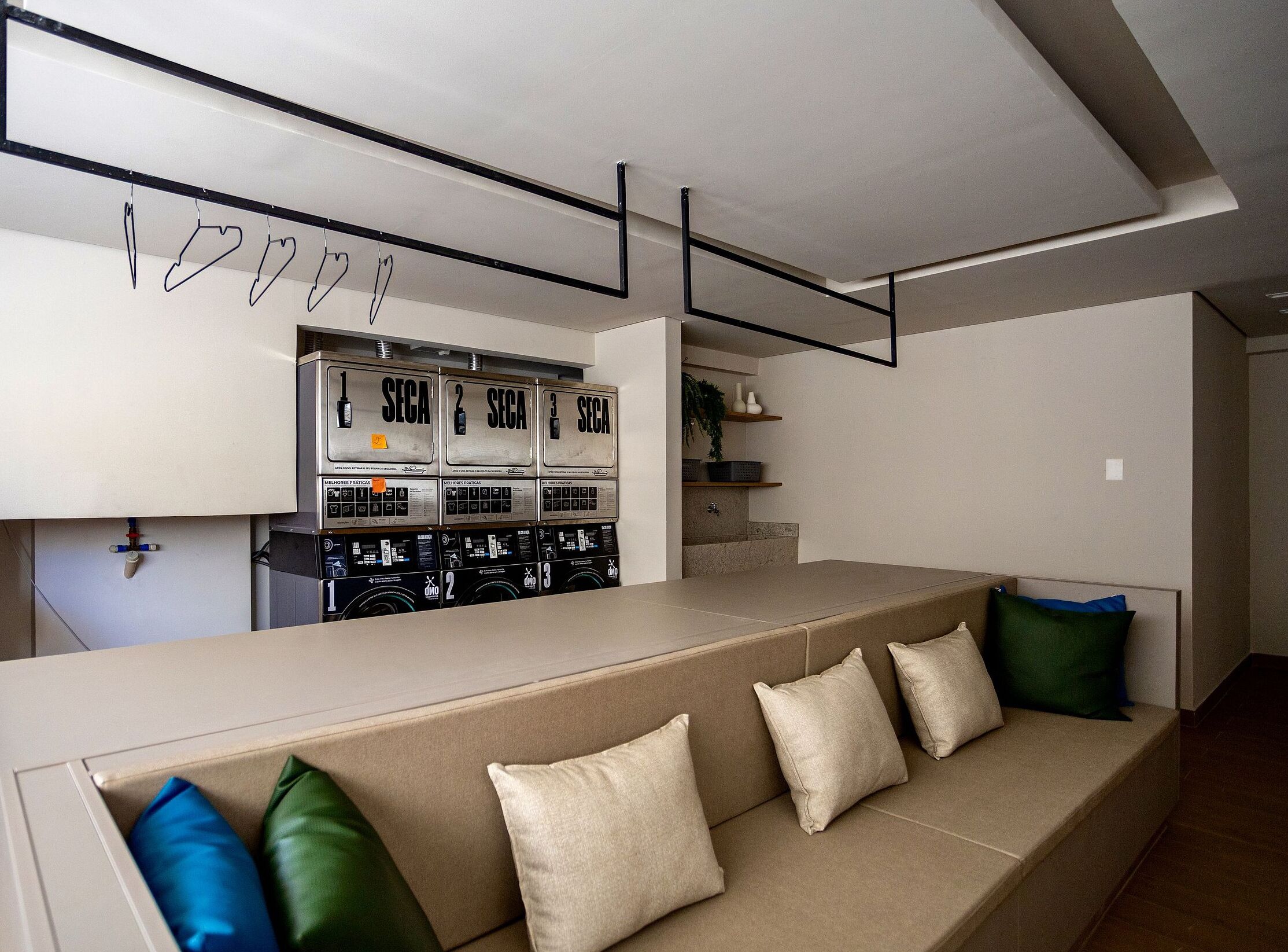 Una cocina moderna con tres lavadoras SECA, un sofá color beige con cojines, y un diseño minimalista.