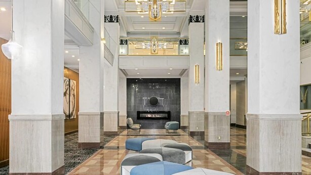 Un hall d’entrée spacieux avec un sol à carreaux, un espace salon central agrémenté de canapés modernes et une cheminée.