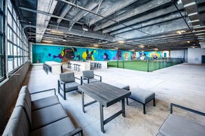 Un espace intérieur moderne doté d’un long banc, d’un comptoir avec des tabourets et d’une fresque colorée sur le mur.
