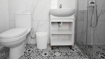 A bathroom with a toilet, sink, and shower. The floor has a patterned tile design.
