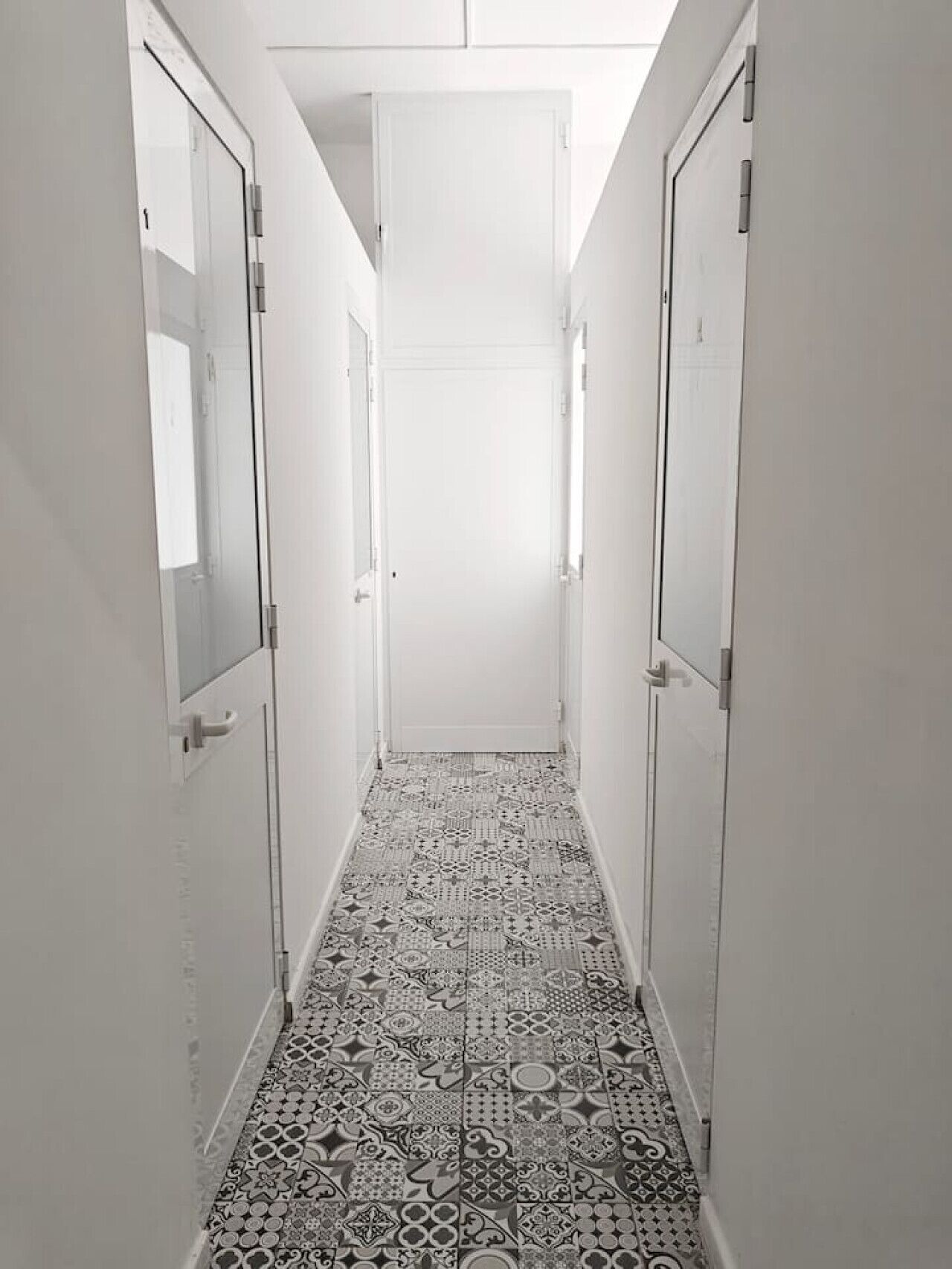 Un pasillo estrecho con baldosas de diseño en el suelo y paredes blancas.