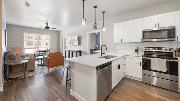 A modern kitchen with white cabinetry, stainless steel appliances, and pendant lighting. - Landing | Stylish 2BD, Clubhouse (Goodyear)