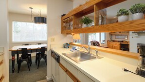 A compact kitchen with a wooden countertop, a built-in sink, and a dining area with a table and chairs. - Sugarbush Escape  Fireplace and Shuttle Access (Warren)