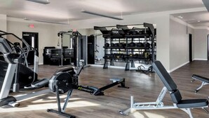 Een moderne sportschool met cardioapparatuur, gewichthefapparatuur en een bank.