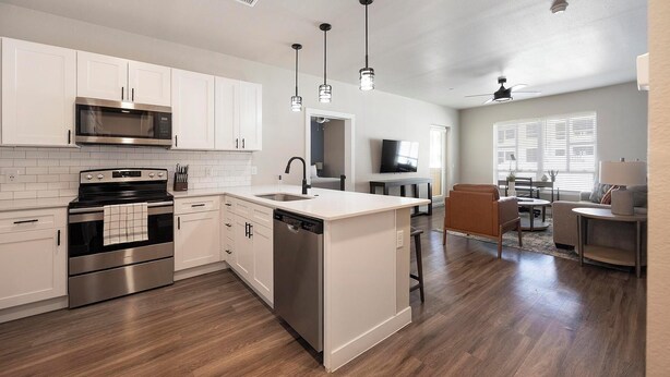 A modern kitchen with stainless steel appliances, a dishwasher, and a dining area with a sofa and table.