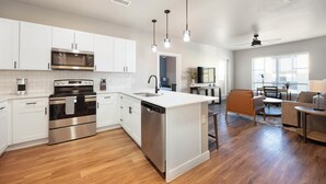 Une cuisine moderne avec des meubles blancs, des appareils en acier inoxydable et un îlot central.