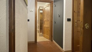 Un pasillo con una puerta de madera, un accesorio de iluminación y una puerta con cerradura.