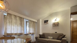 Una sala de estar con una mesa de comedor de vidrio, un sofá y una puerta de madera.