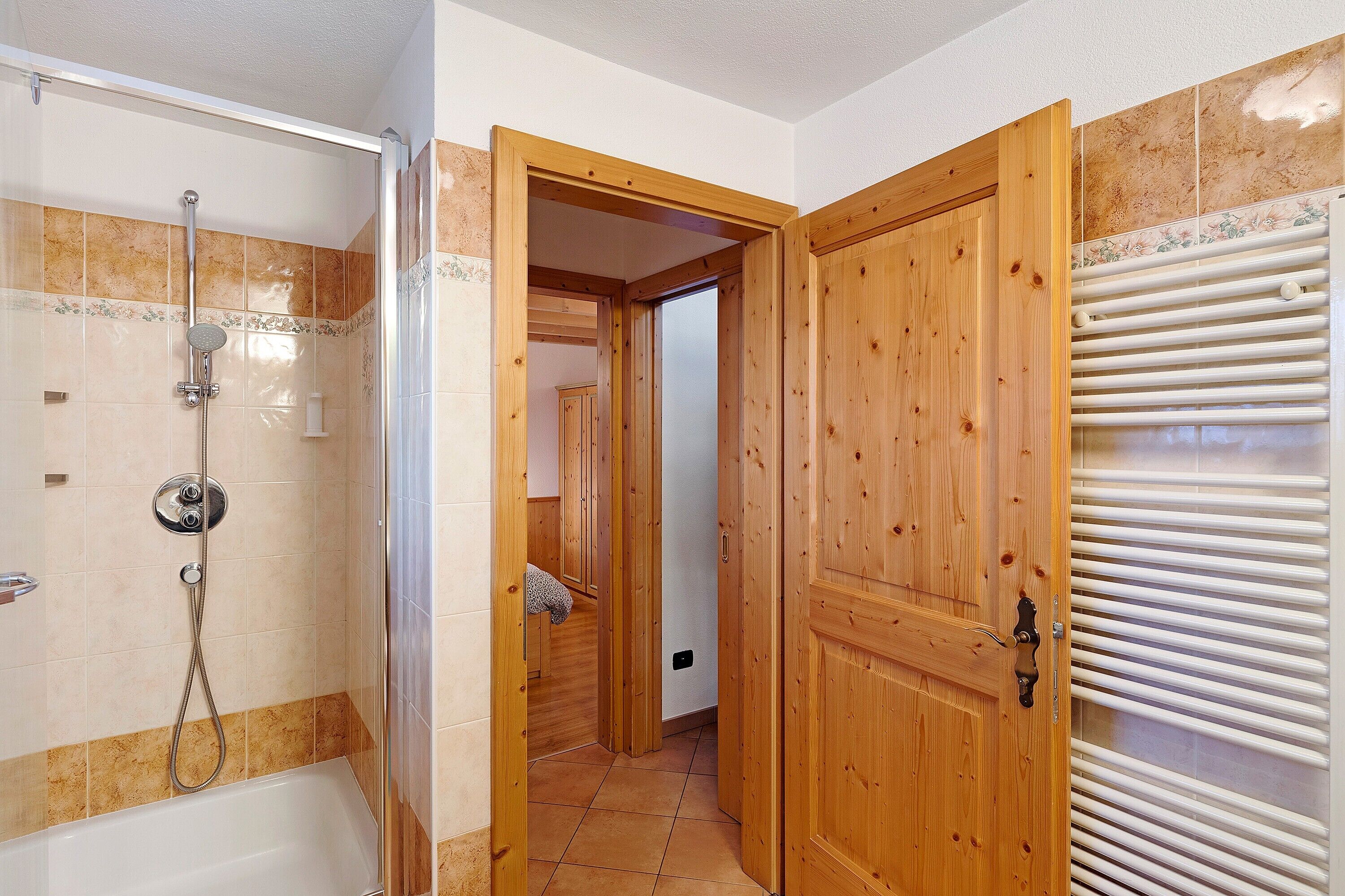 A bathroom with a shower, a wooden door, and a towel rack.