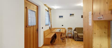 Ein Zimmer mit einer Holzbank, einem Tisch, einem Stuhl und einem Schrank.