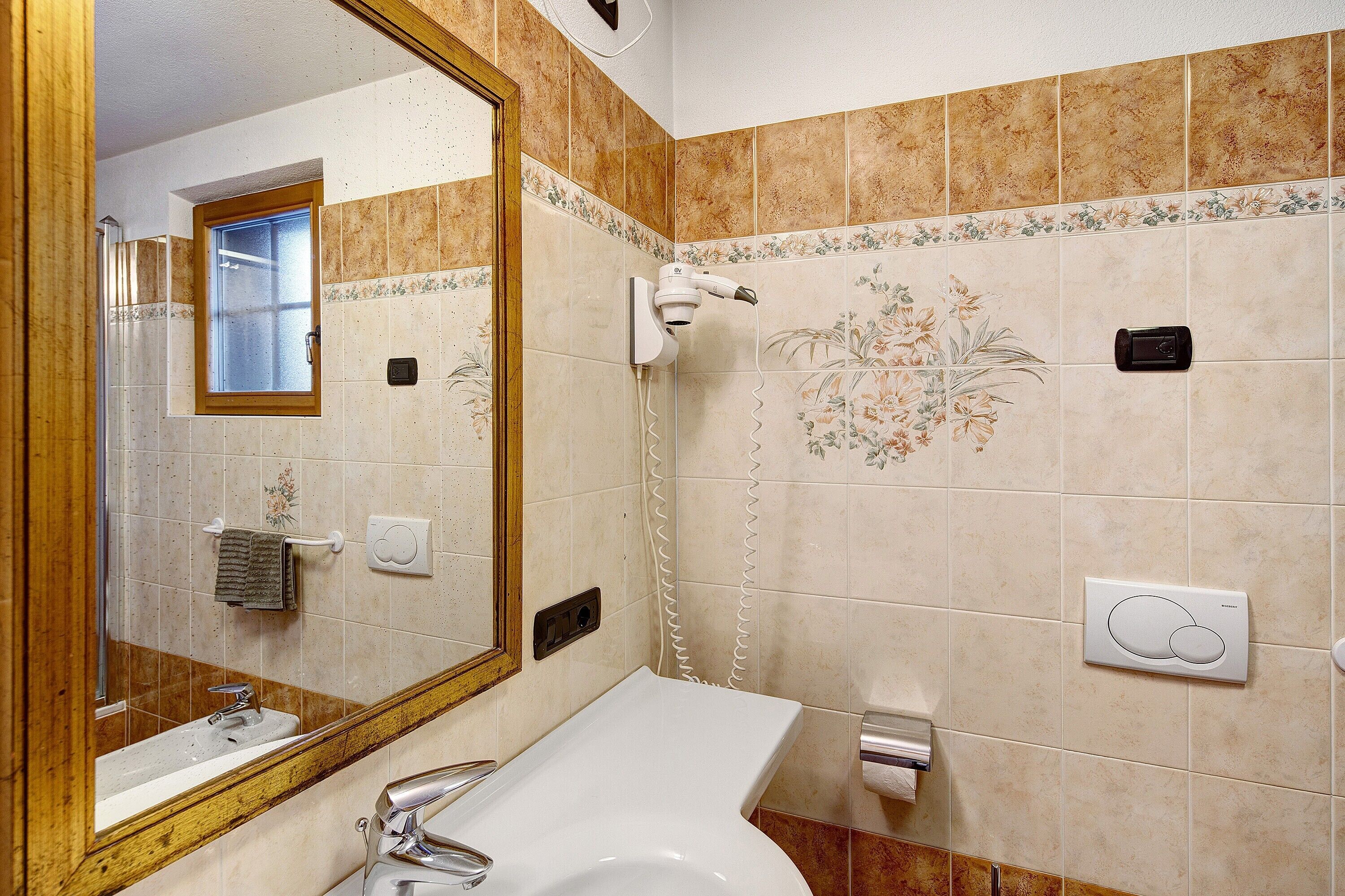 Une salle de bain équipée d’un lavabo, d’un miroir et d’un sèche-cheveux fixé au mur.