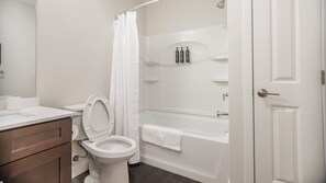 A bathroom with a toilet, sink, and bathtub. - Landing Apartments Vernon (Vernon)