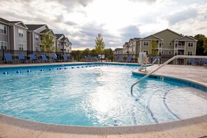 A swimming pool with lounge chairs and a lifeguard stand. - Landing Apartments Vernon (Vernon)